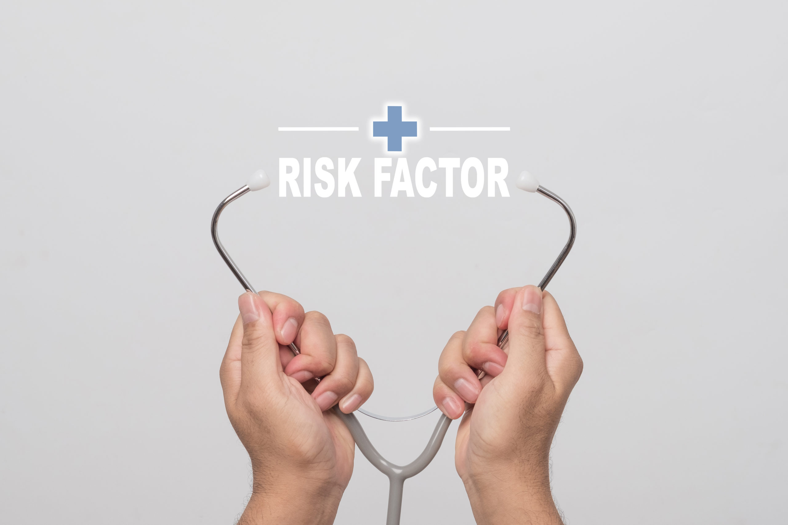 Hands holding a stethoscope and word "RISK FACTOR" medical concept.